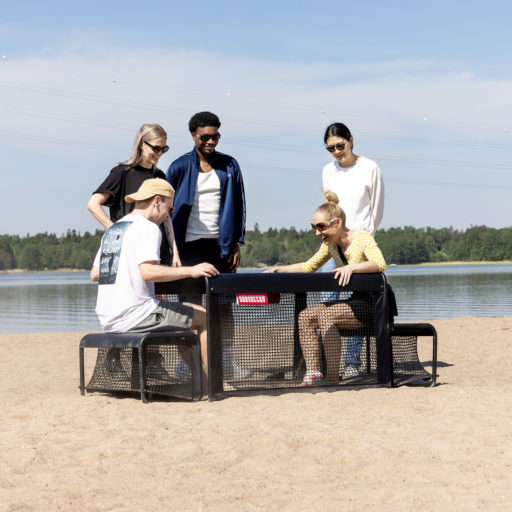 Friends playing a competitive round of sit-down football using the SubSoccer S3 portable pitch on the sand