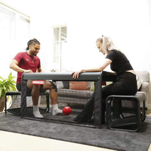 Couple in active play on SubSoccer S7 bench soccer game inside a modern home