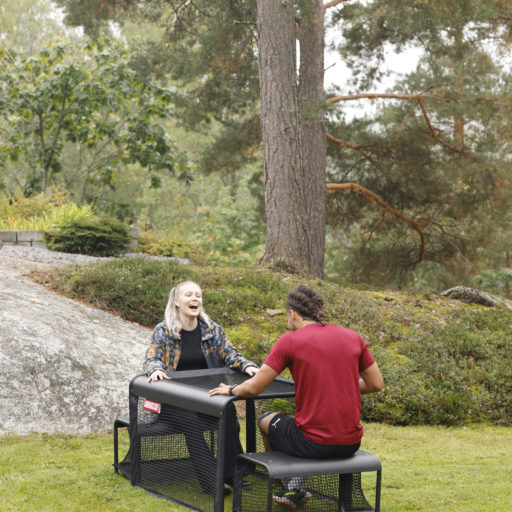 Couple playing SubSoccer S7 bench soccer game outdoors in a garden backyard setting