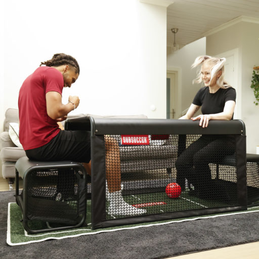 Man playing SubSoccer S7 bench soccer game indoors in a living room, close-up view of the playing field