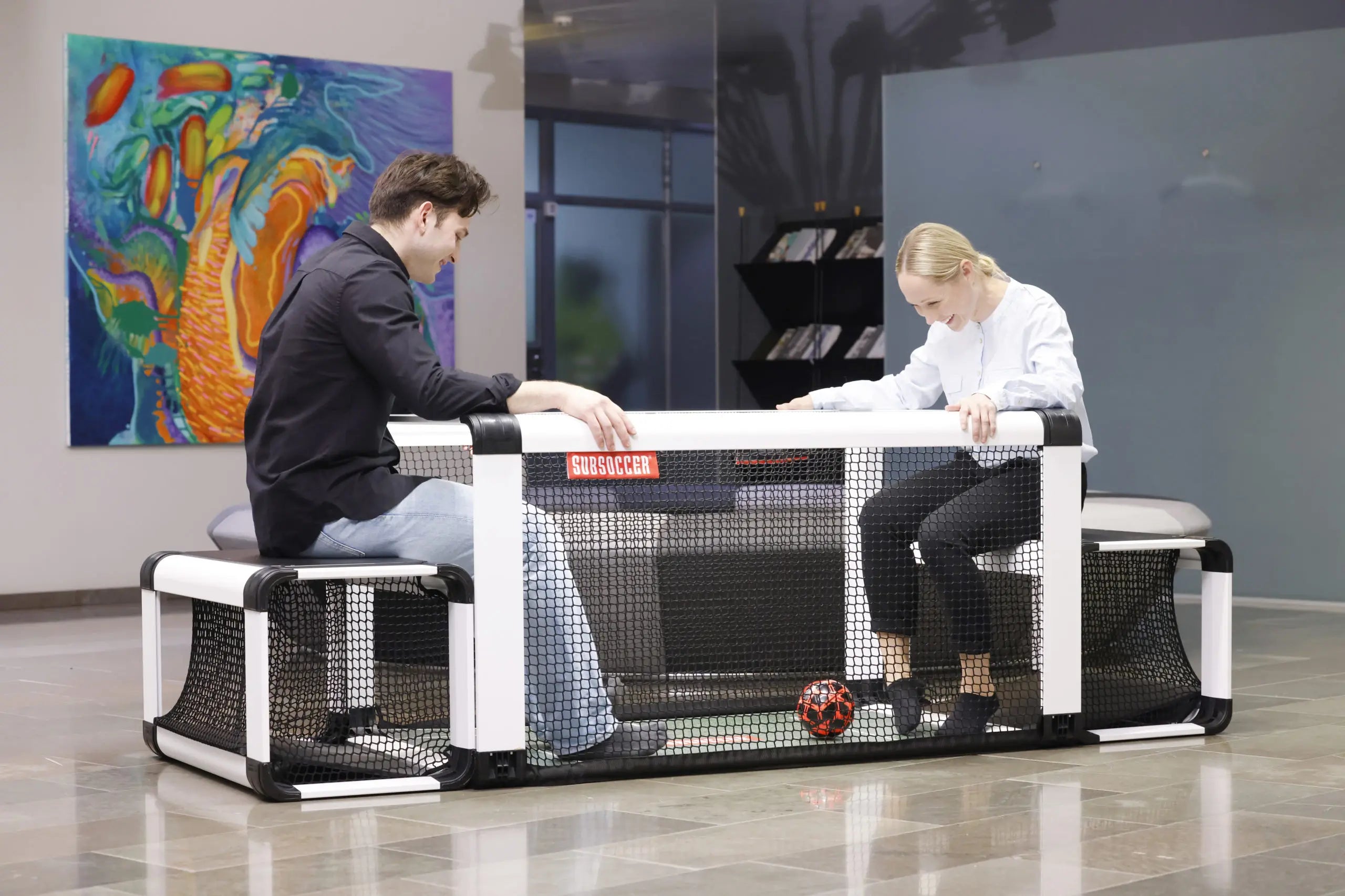 Two players competing on the SubSoccer S7 bench soccer game in an office break room fetchpriority=