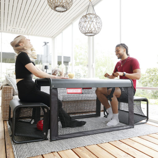 Man and woman playing SubSoccer S7 bench soccer game on an outdoor covered terrace