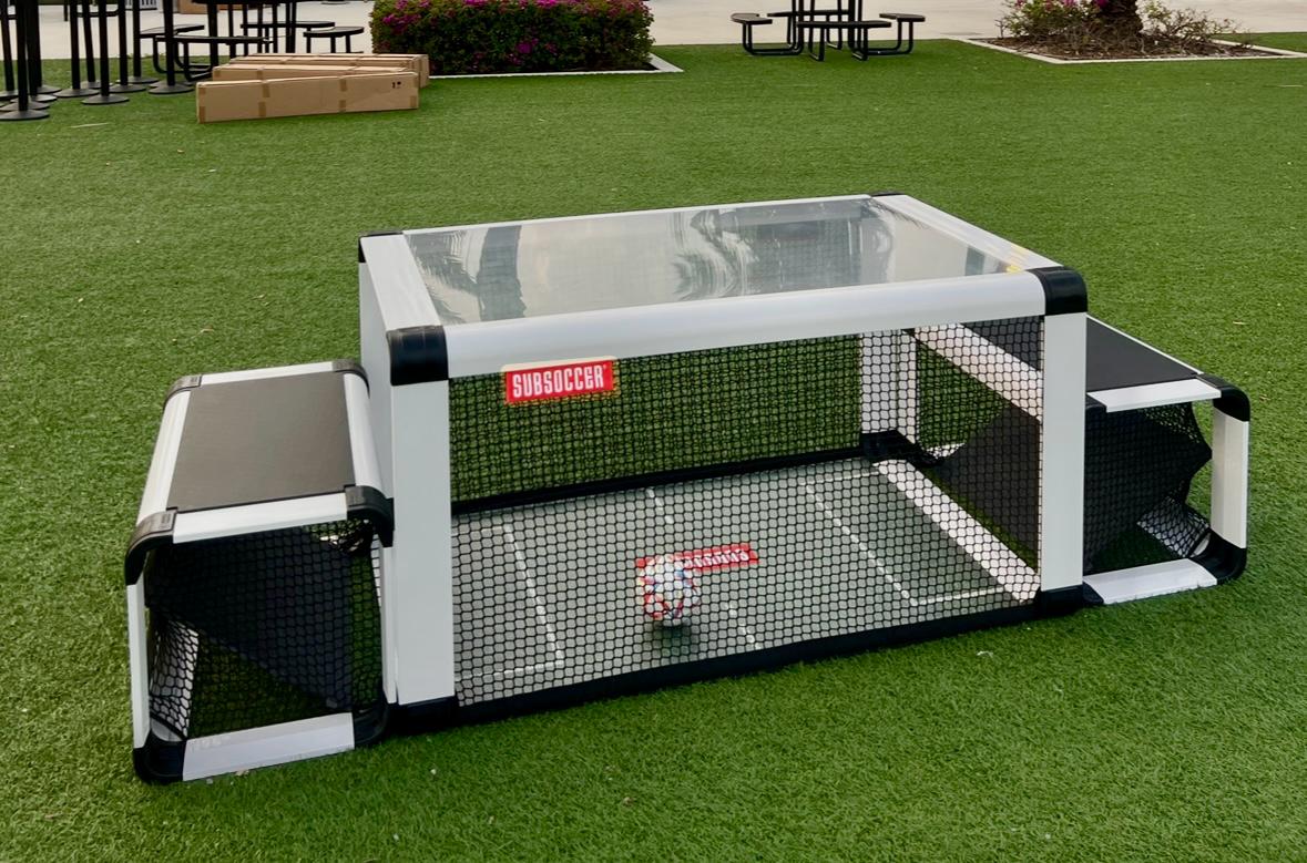 SubSoccer S7 black bench soccer game set up on a garden lawn outdoors